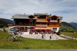 a man riding a bike in front of a building at Hôtel les skieurs in Bellevaux