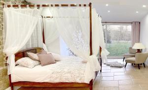 ein Schlafzimmer mit einem Himmelbett und einem Fenster in der Unterkunft Domaine de la Tranquillité V in Noyal-Muzillac