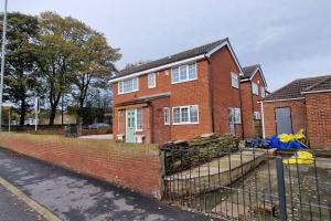 a brick house with a fence in front of it at Luxury 3 Bed Detached House in Farsley
