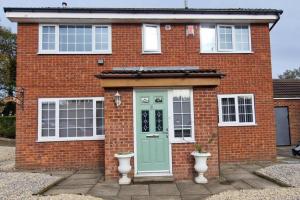 a red brick house with a green door at Luxury 3 Bed Detached House in Farsley