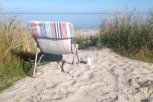 una sedia seduta sulla sabbia della spiaggia di Havsnära Motorbåt 12 Cyklar 18+Beds VedBastu Hav! a Djurhamn