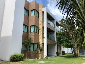 a large building with palm trees in front of it at Iloa Residence Apt Premium -Quarto e sala climatizado in Barra de São Miguel