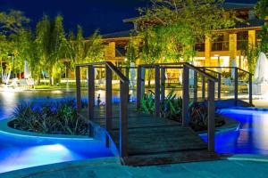 a wooden staircase leading to a pool at night at Iloa Residence Apt Premium -Quarto e sala climatizado in Barra de São Miguel