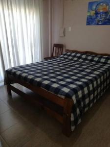- un lit avec une couverture en damier bleu et blanc dans l'établissement Departamento de temporada para 6 personas, à Mar de Ajó