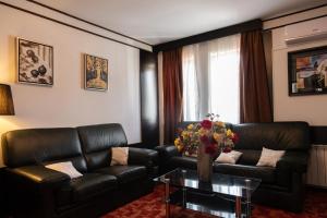 a living room with black leather furniture and a vase of flowers at VILA COMO EN CASA - FREE PARKING in Sarajevo
