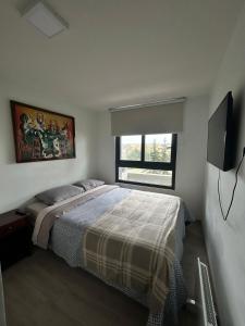 a bedroom with a bed and a flat screen tv at Hermoso Depto para 4 personas ,con Arcade de juegos y vista hacia las Dunas y el Mar in Concón