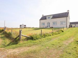 une maison dans un champ à côté d'une clôture dans l'établissement Park Cottage, à Carinish