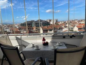 a table and chairs with a view of a city from a window at Purple apartment- in Prizren +13 photos