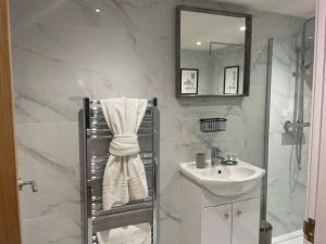 y baño blanco con lavabo y ducha. en Pentrebach House by M-GroupSA en Troed-y-rhiw