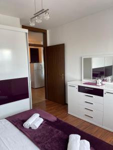 uma cozinha branca com uma cama e um lavatório em Purple apartment- em Prizren
