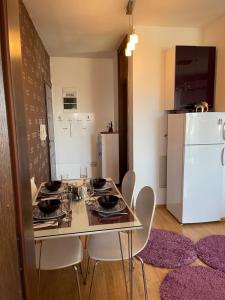 uma cozinha com uma mesa e cadeiras e um frigorífico em Purple apartment- em Prizren