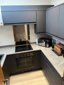 a kitchen with black cabinets and a stove top oven at The Curious Apartment, Cheltenham in Cheltenham