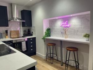 a kitchen with a bar with a neon sign on the wall at Pentrebach House by M-GroupSA in Troed-y-rhiw