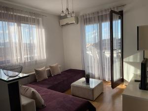 uma sala de estar com um sofá e uma grande janela em Purple apartment- em Prizren