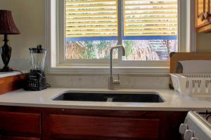 a kitchen sink in front of a window with blinds at Casa Palma Placencia in Placencia Village