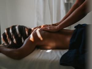 a woman laying on a bed with her hands on her back at Les Elmes - Hôtel & Spa in Banyuls-sur-Mer