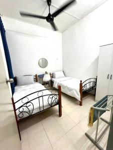 sypialnia z 2 łóżkami i wentylatorem sufitowym w obiekcie Homestay Eco Rengas Jaya w mieście Padang Rengas