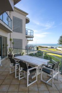 - une table et des chaises sur une terrasse avec vue sur l'océan dans l'établissement The Reef Beachfront Apartments, à Mount Maunganui