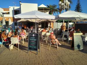 a group of people sitting at a restaurant under umbrellas at Puerta del Sol in Caleta De Fuste