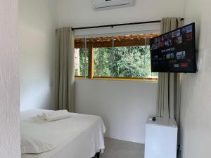 Habitación con cama y TV de pantalla plana. en Apartamentos com cachoeira no quintal, en Ilhabela
