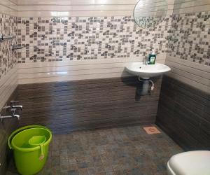 a bathroom with a sink and a green bucket at Vythiri Garden in Vythiri