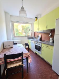 une cuisine avec des armoires jaunes, une table et une fenêtre dans l'établissement Appartement Les Oliviers, à Nice