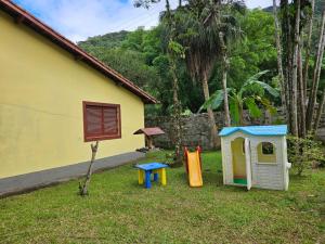 un patio con dos estructuras de juego y una casa en Pousada da Mary en Ubatuba