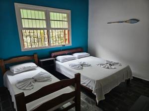 two twin beds in a room with a window at Pousada da Mary in Ubatuba