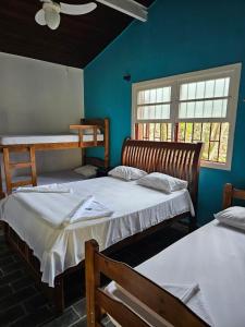 2 camas en una habitación con paredes azules y 2 ventanas en Pousada da Mary en Ubatuba