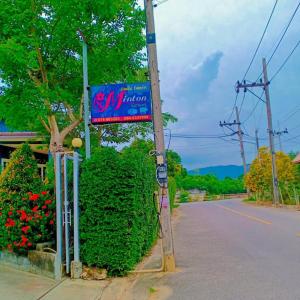 een bord aan de kant van een straat naast een struik bij Minton Resort มิลตั้น รีสอร์ท in Ban Kohong