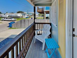 a porch with two white chairs and a blue bench at Tranquil Cove in Port Aransas