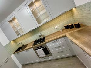 a kitchen with white cabinets and a wooden counter top at Białe Noce Apartament in Biała Podlaska +3 photos