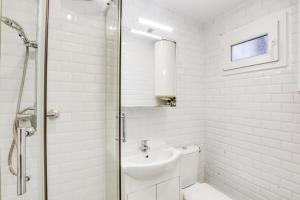 ein weißes Bad mit einem Waschbecken und einer Dusche in der Unterkunft 9 min de l'hippodrome avec terrasse privée in Suresnes
