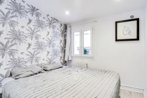 ein Schlafzimmer mit einem Bett mit einer tropischen Tapete in der Unterkunft 9 min de l'hippodrome avec terrasse privée in Suresnes
