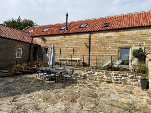 a patio with a table and chairs and a building at Owl Barn in Whitby