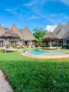 a resort with a swimming pool and thatched huts at MITI Beach Bungalows in Nungwi