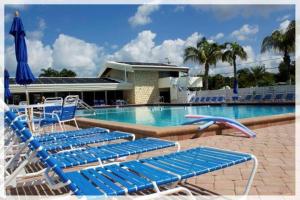una piscina con tumbonas azules y una sombrilla azul en Villa 47 - Aloha Kai Vacation Villas, en Siesta Key