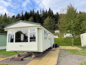 una pequeña caravana amarilla estacionada en un patio en Pass the Keys Charming and Cosy Holiday Home in Beautiful Park, en Beattock