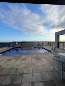 a man standing on top of a building with a swimming pool at Ipanema Flat - Vieira Souto 500 in Rio de Janeiro