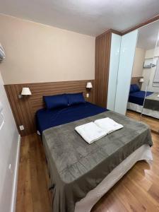 a bedroom with a bed with blue sheets and a mirror at Flat Barra - Parque das Rosas in Rio de Janeiro