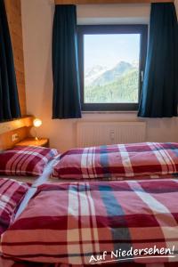 two beds in a room with a window at Auf Niedersehen Apartment National Park Höhe Tauern in Hollersbach im Pinzgau