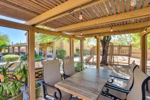 een houten tafel en stoelen onder een houten pergola bij Cave Creek Getaway with Pool and Outdoor Kitchen! in Cave Creek