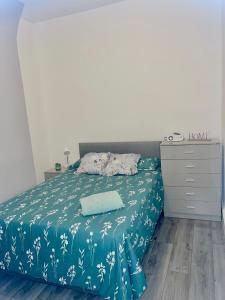 a bedroom with a bed with a blue blanket and a dresser at Family House in Liverpool