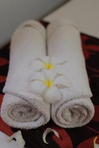 two towels with flowers on them on a bed at D Plus B&B Negombo in Negombo