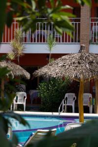 2 Stühle und Sonnenschirme neben einem Pool in der Unterkunft Bungalows Las Tortugas in Lo de Marcos