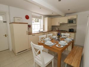 - une cuisine avec une table en bois et des chaises blanches dans l'établissement Harbour Tales, à Weymouth