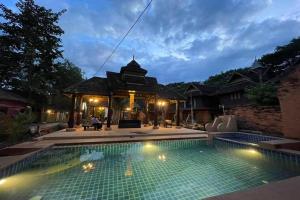 a swimming pool in front of a house with a gazebo at Baan Tawai Lanna Resort in Hang Dong