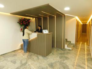 two people standing at a counter in a lobby at HOTEL MX BOGOTA in Bogotá