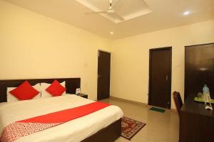 Hotel Castle في بهيراهاوا: غرفة نوم مع سرير مع وسائد حمراء ومكتب