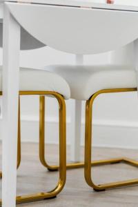 une table blanche avec des jambes dorées et une chaise blanche dans l'établissement Charming Flat In Shepherds Bush, à Londres